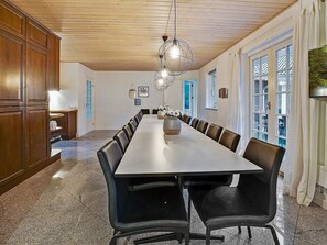A long dining table with chairs, a wooden ceiling, and a chandelier. - 5 Star Holiday Home in Frederiksvaerk (Frederiksvaerk)