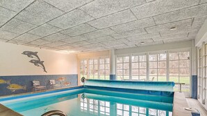An indoor swimming pool with clear glass walls, a diving board, and a dolphin mural on the wall. - 5 Star Holiday Home in Frederiksvaerk (Frederiksvaerk)