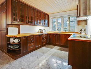 A kitchen with wooden cabinets, a countertop, a sink, and a window. - 5 Star Holiday Home in Frederiksvaerk (Frederiksvaerk)