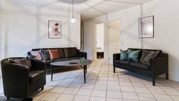 A living room with two black sofas, a coffee table, and a hanging light fixture.