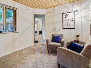 A room with a wooden ceiling, a large window, a framed artwork, and a seating area with two armchairs and a small table. - 5 Star Holiday Home in Frederiksvaerk (Frederiksvaerk)