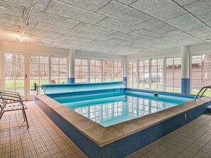 A large indoor swimming pool with clear glass walls, a tiled floor, and a bench along one side. - 5 Star Holiday Home in Frederiksvaerk (Frederiksvaerk)