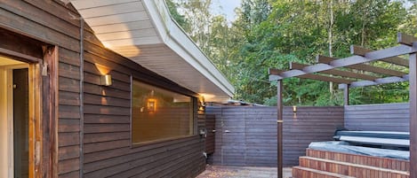 Une terrasse en bois agrémentée d’une pergola et d’un escalier menant à un espace de détente abrité.