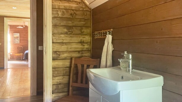 A bathroom with a wooden wall, a sink, and a chair. - 4 Star Holiday Home in Orsjo (Örsjö)