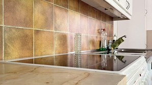A kitchen with a tiled backsplash, a stainless steel countertop, and a built-in oven. - 4 Star Holiday Home in Orsjo (Örsjö)