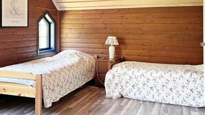 A room with two wooden beds, a window with a view, and a wall-mounted lamp. - 4 Star Holiday Home in Orsjo (Örsjö)