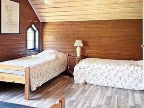 Une chambre avec deux lits en bois, une fenêtre donnant sur un beau paysage et une lampe fixée au mur.