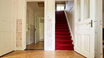 A hallway with a red carpet leading to a staircase.