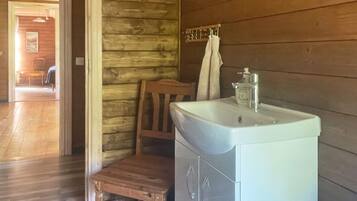 A bathroom with a wooden wall, a white sink, and a wooden chair.