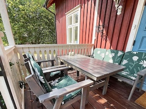 A wooden deck with a table and chairs, a window, and a blue door. - 4 Star Holiday Home in Orsjo (Örsjö)