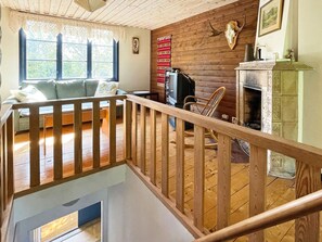 A wooden-floored living room with a sofa, a television, and a fireplace. - 4 Star Holiday Home in Orsjo (Örsjö)
