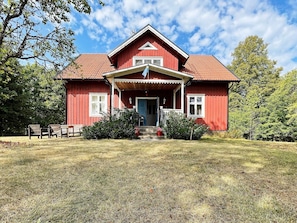 A red wooden house with a porch, a front door, and a small staircase leading up to the entrance. - 4 Star Holiday Home in Orsjo (Örsjö)