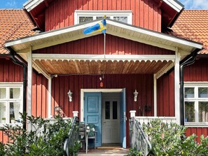 A red wooden house with a blue door, a covered porch, and a flag. - 4 Star Holiday Home in Orsjo (Örsjö)