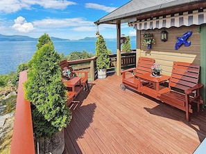 A wooden deck with outdoor furniture, a hanging chair, and a view of the sea. - Holiday Home in Hundeidvik (Sykkylven)