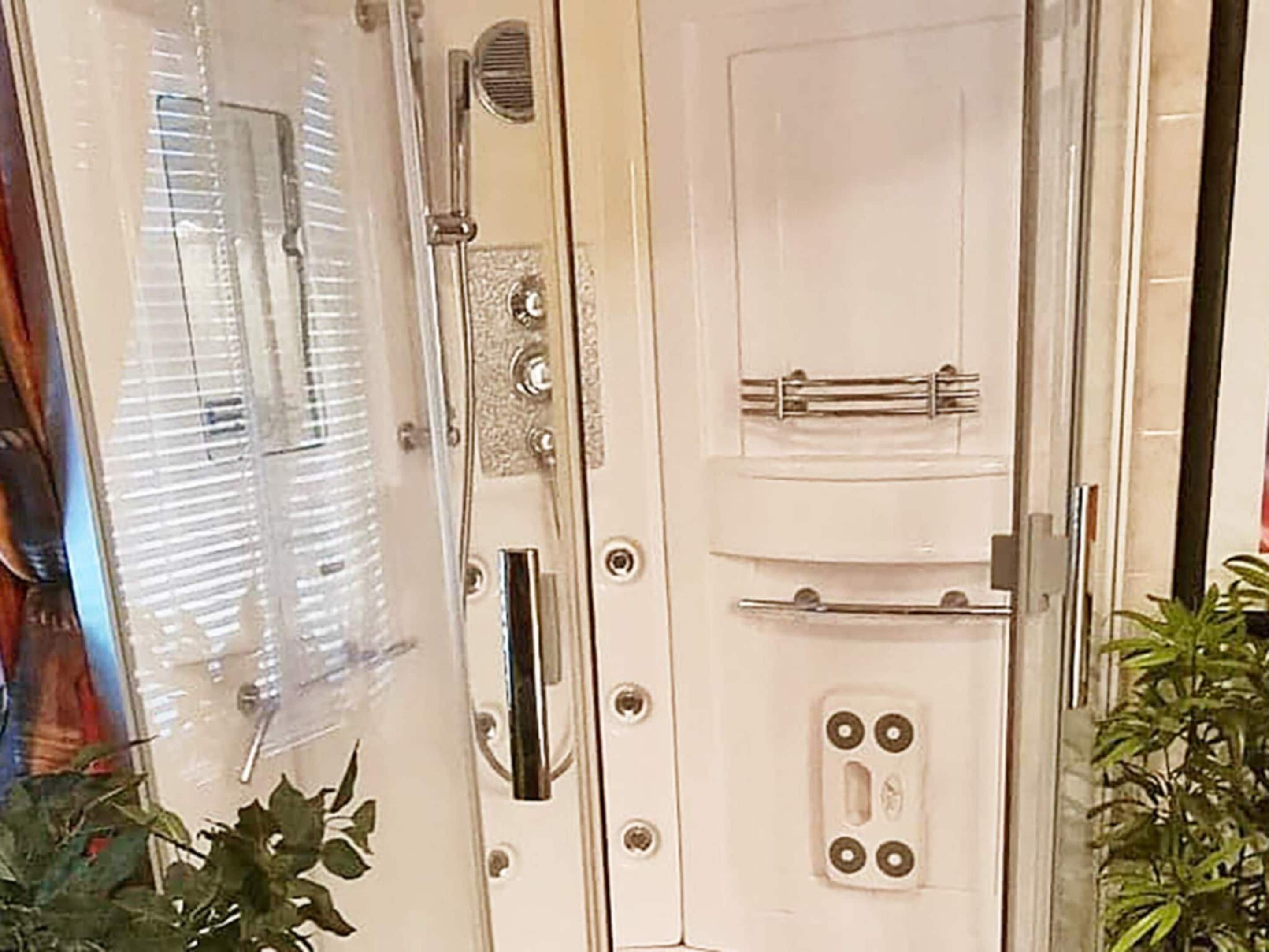 A white door with a towel rack, a shower control panel, and a window with blinds.