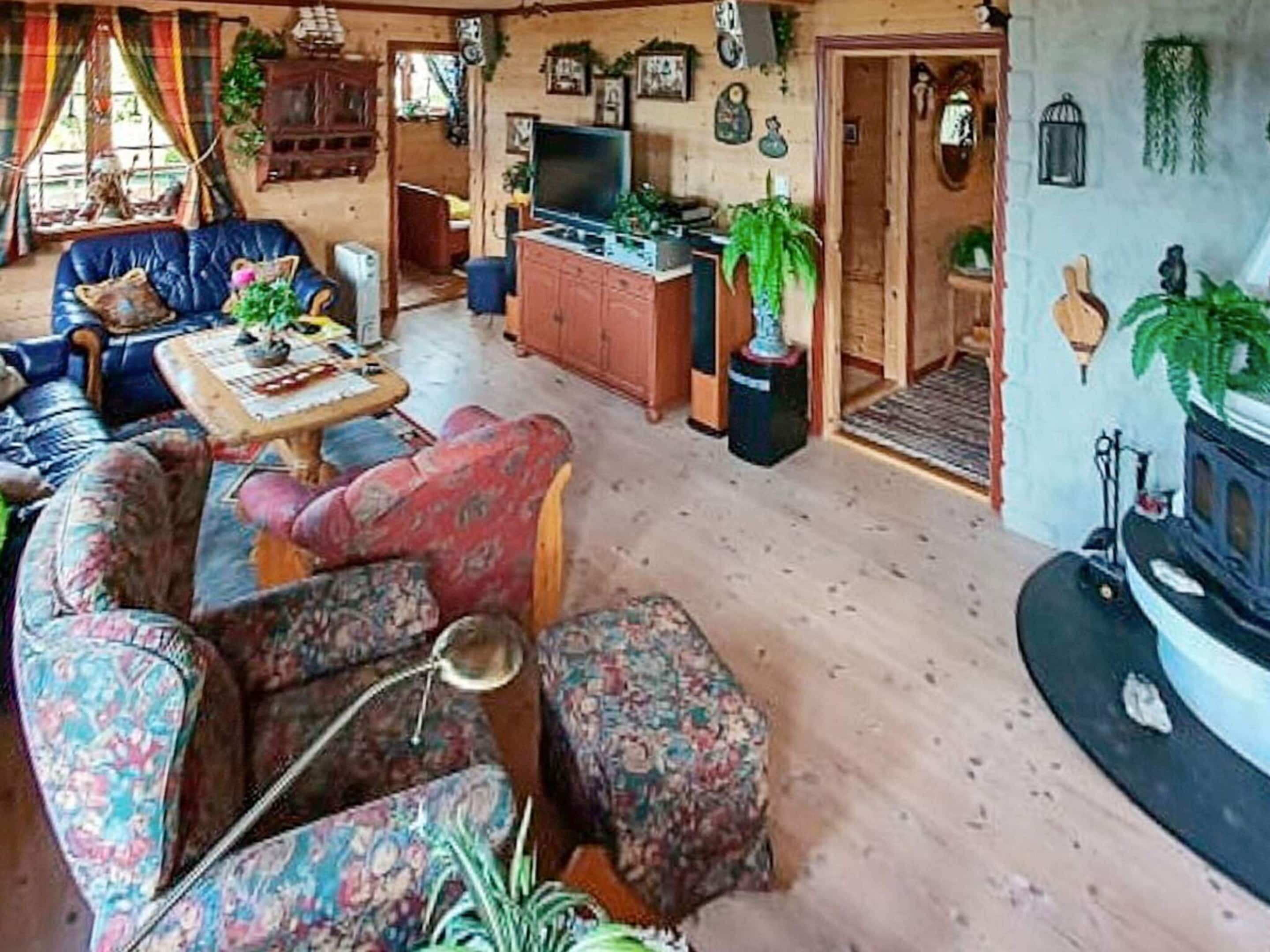 Un salon confortable avec un ensemble de canapés, une table basse et un téléviseur. On y trouve une cheminée et une porte qui donne sur une autre pièce.