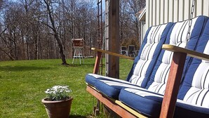 A wooden deck with a blue-striped sofa, a ladder, and a birdhouse. - 4 Person Holiday Home in Romelanda (Romelanda)