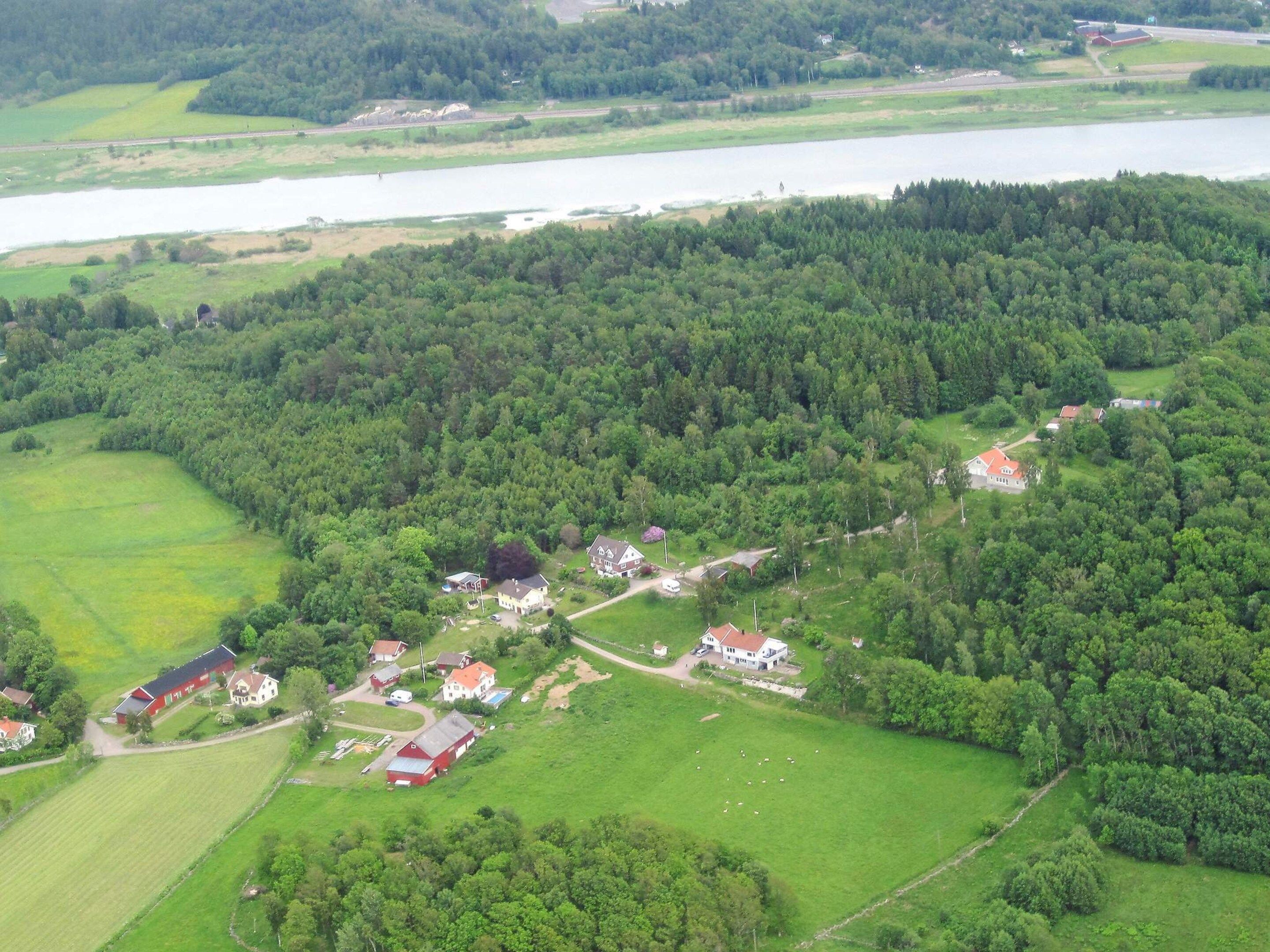 An aerial view of a rural area with scattered houses, a lake, and surrounding greenery.