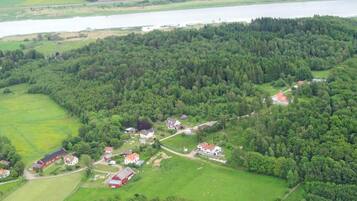 An aerial view of a rural area with scattered houses, a lake, and surrounding greenery.