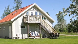 A two-story building with a red roof, a balcony, and a staircase leading to the upper floor. - 4 Person Holiday Home in Romelanda (Romelanda)