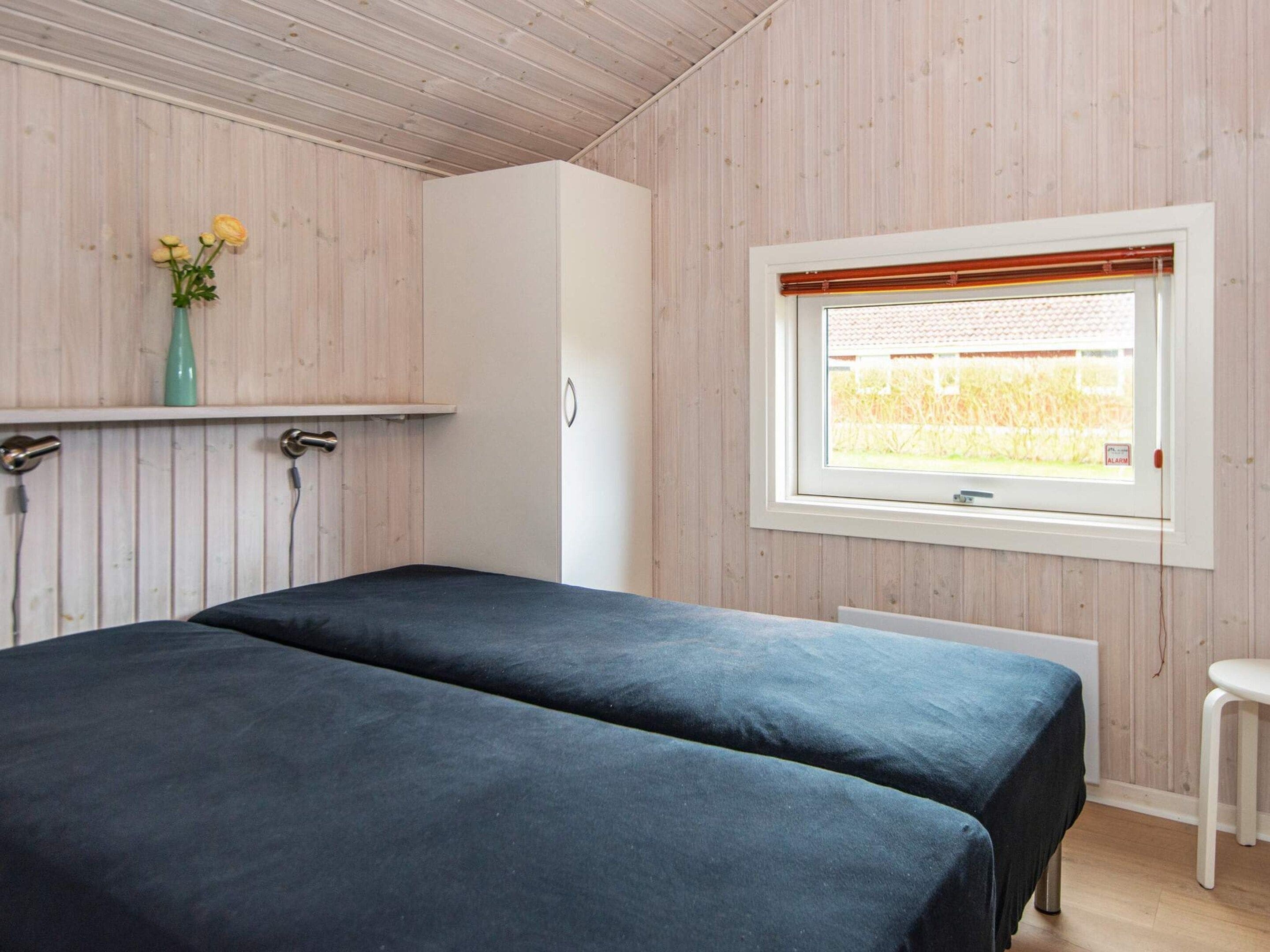 A bedroom with two beds, a window with a view of a field, and a small table.