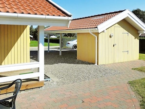 A building with a covered patio area, a car parked in the background, and a gravel driveway. - 6 Person Holiday Home in Nordborg-by Traum (Nordborg)