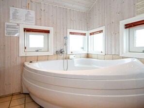A bathroom with a large bathtub, wooden walls, and two windows with wooden blinds. - 6 Person Holiday Home in Nordborg-by Traum (Nordborg)