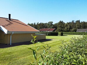 A building with a red-tiled roof, a wooden exterior, and a well-maintained lawn.
