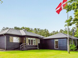 A two-story building with a flagpole, a staircase, and a grassy yard. - 8 Person Holiday Home in Roslev-by Traum (Roslev)