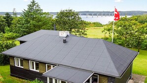 A house with a dark roof, a chimney, and a flagpole with a flag. - 8 Person Holiday Home in Roslev-by Traum (Roslev)