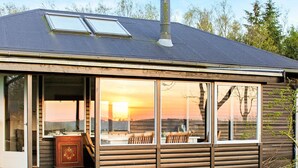 Uma cabana com uma janela grande, chaminé e um terraço.