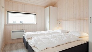 A bedroom with a bed, a window, and a wardrobe. - Holiday Home in Großenbrode (Grossenbrode)