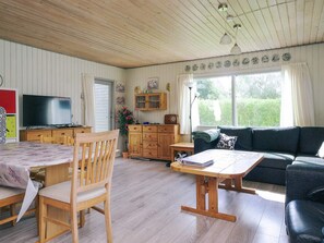 A cozy living room with a wooden table, a sofa, and a television.