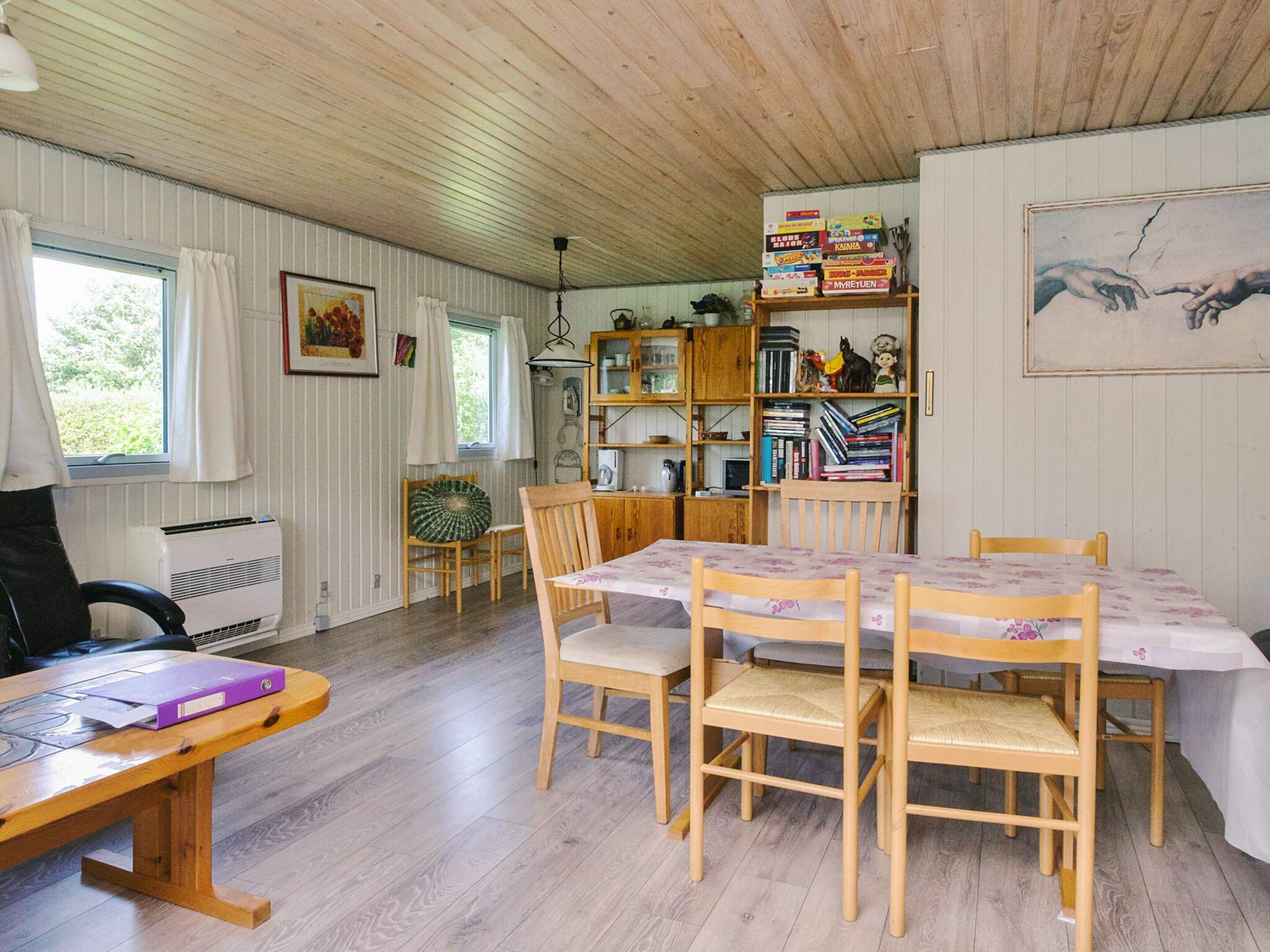 A cozy room with a wooden table and chairs, a bookshelf, and a radiator.
