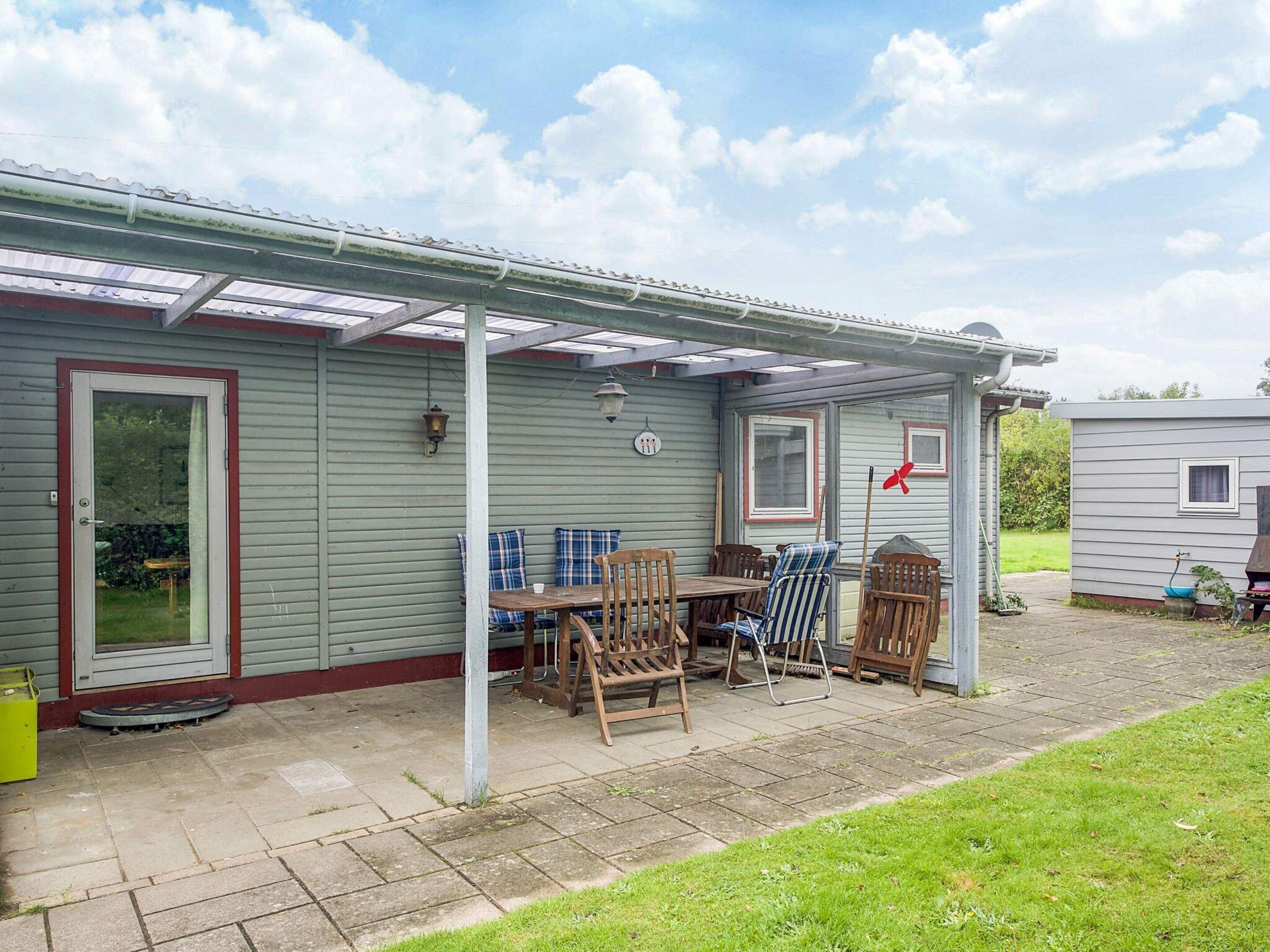 A covered patio area with a table and chairs, a small grill, and a window.