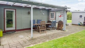 A covered patio area with a table and chairs, a small grill, and a window. - 6 Person Holiday Home in Eskebjerg-by Traum (Eskebjerg)