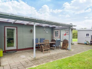 A covered patio area with a table and chairs, a small grill, and a window. - 6 Person Holiday Home in Eskebjerg-by Traum (Eskebjerg)
