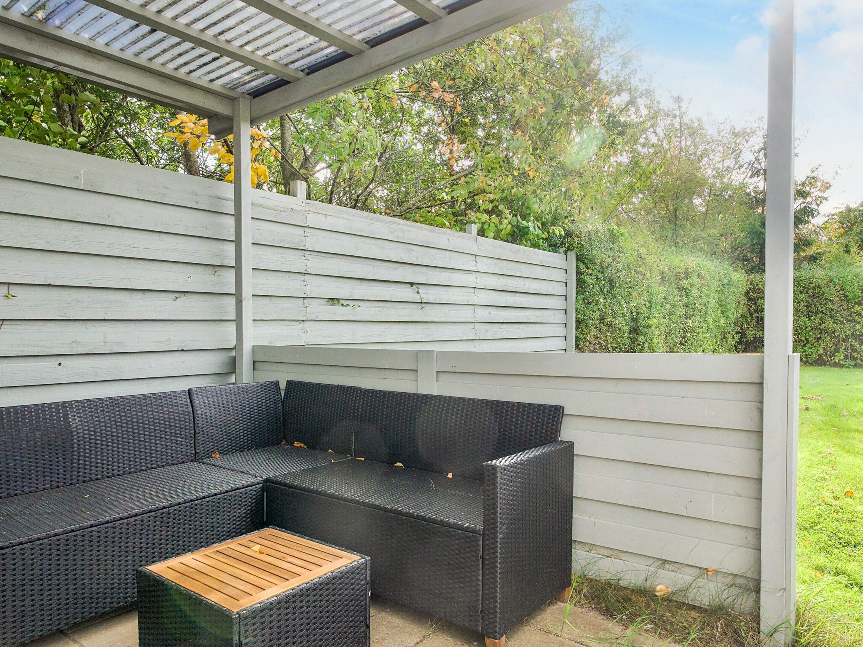A covered outdoor seating area with a sectional sofa and a coffee table.