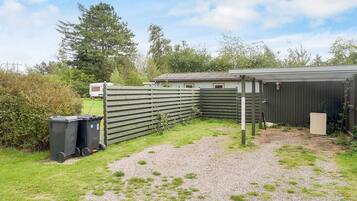 A fenced outdoor area with a gravel path, a small shed, and a trailer in the background.