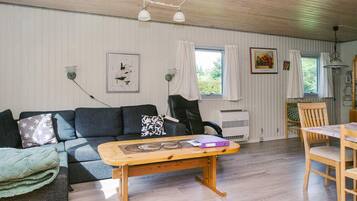 A room with a sofa, a wooden table, a chair, and a bed.