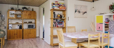 A cozy room with wooden furniture, a dining table, and a bookshelf filled with books and games.