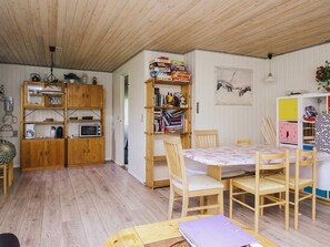A cozy room with wooden furniture, a dining table, and a bookshelf filled with books and games.