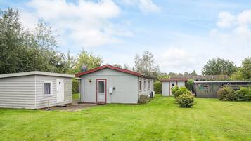 A row of small, single-story mobile homes with red trim and a grassy yard.