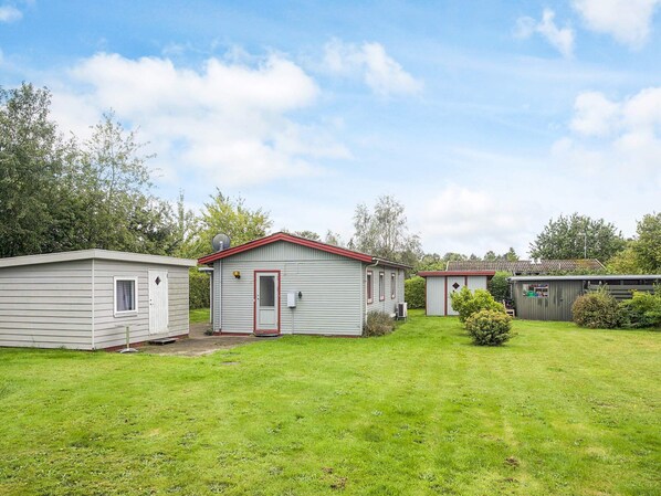 A row of small, single-story mobile homes with red trim and a grassy yard.