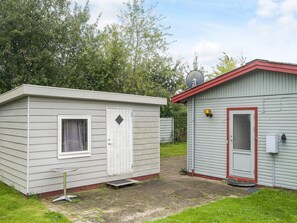 A small, single-story RV with a white exterior and red roof. It features a door with a window, a small porch area, and a satellite dish on the roof. - 6 Person Holiday Home in Eskebjerg-by Traum (Eskebjerg)