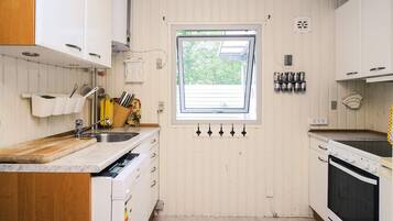 A compact kitchen with white cabinetry, a built-in oven, and a window providing natural light.