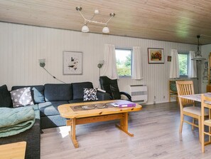 A cozy living room with a sofa, a wooden coffee table, and a dining area with a table and chairs.