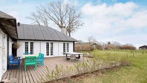 Una casa con terraza de madera, una mesa y sillas.