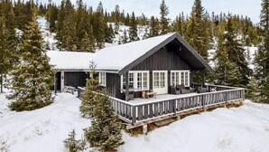 A cabin with a porch, surrounded by snow and trees. - 4 Star Holiday Home in Favang (Ringebu)