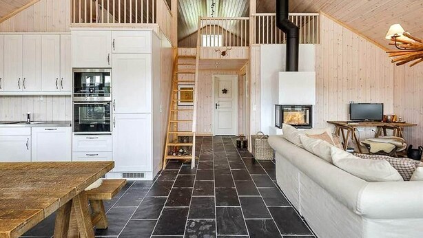 A spacious loft-style living area with a kitchen, a fireplace, a wooden staircase, and a cozy seating area. - 4 Star Holiday Home in Favang (Ringebu)
